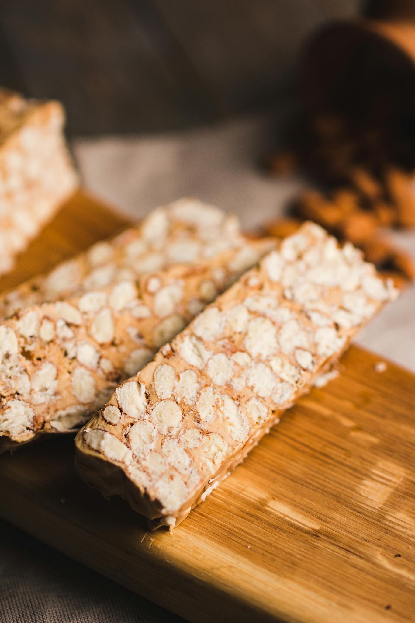 Close-up of peanut nougat bars on a wooden cutting board, showcasing their texture.
