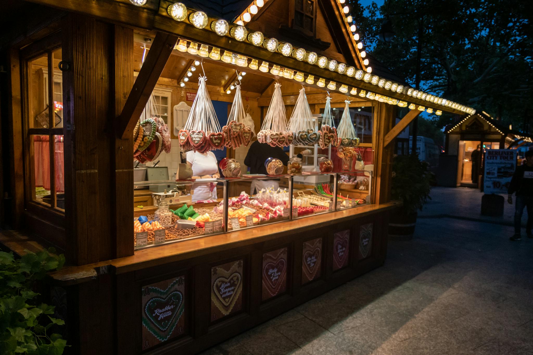 Explore Berlin's vibrant night market with a cozy sweets stall, offering traditional treats and festive lights.